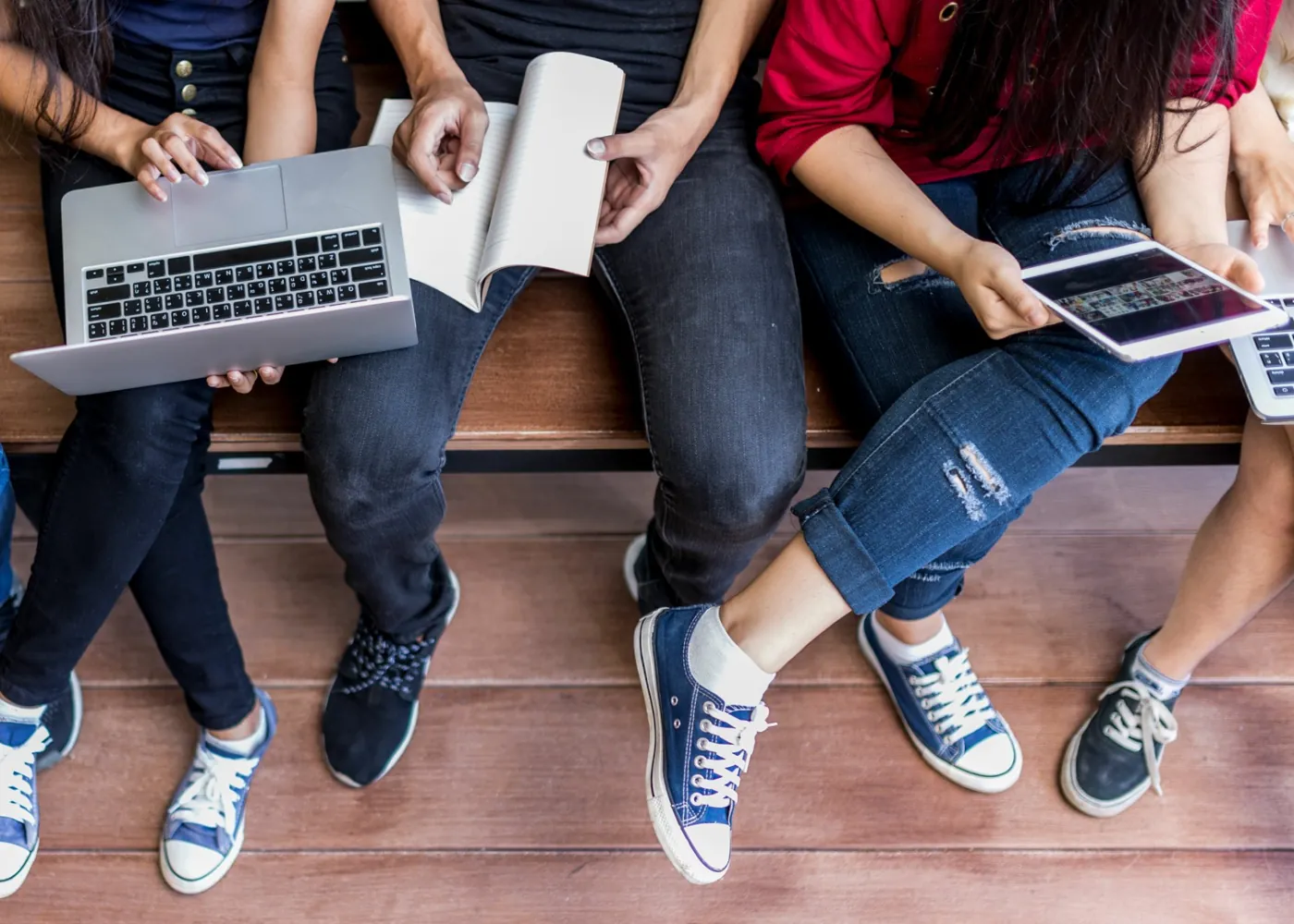 Students sharing a laptop, notebook, and tablet